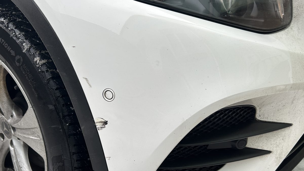 Vordere Fahrzeugecke mit Rad und beschädigtem Stoßfänger